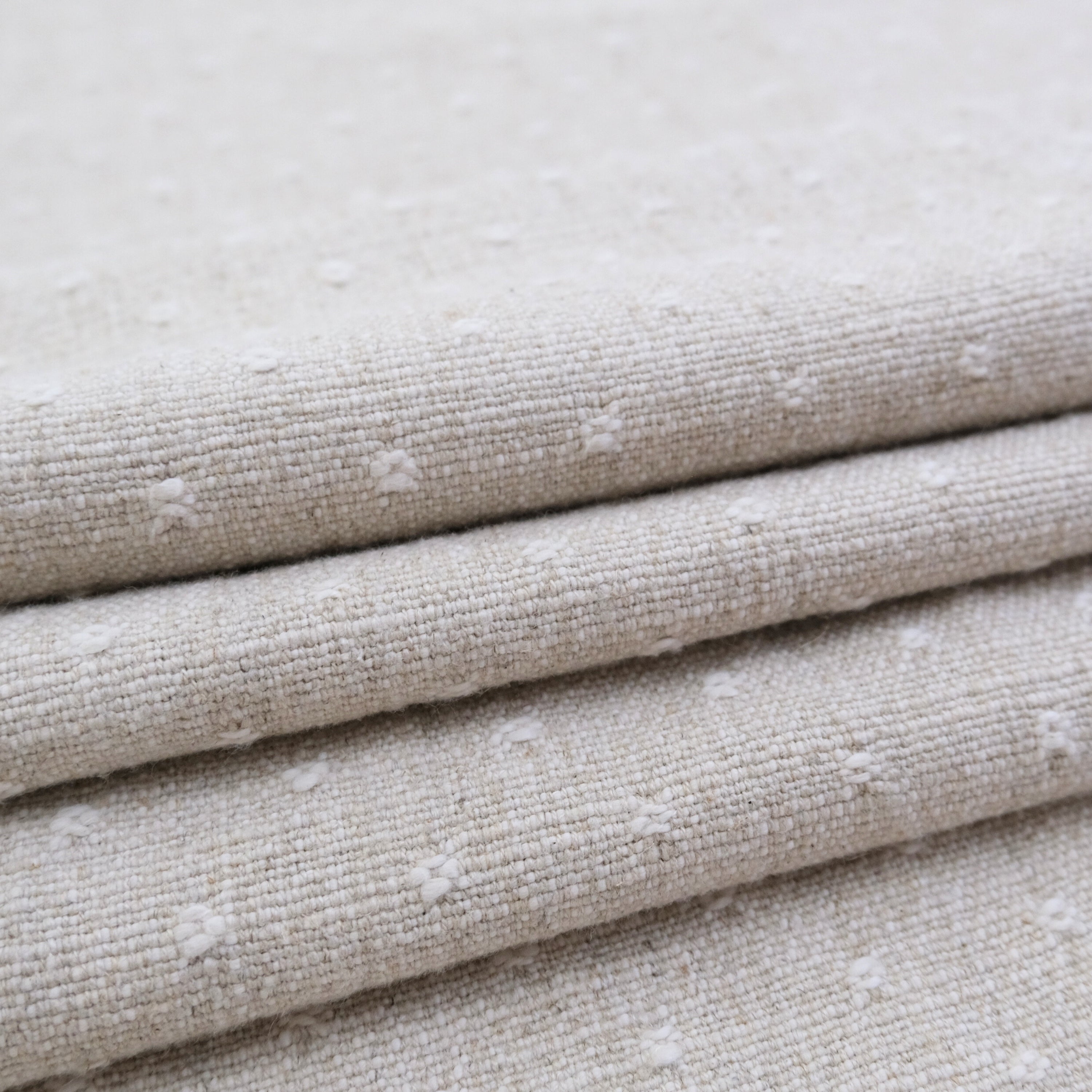 A close-up view of a folded fabric with a textured, beige-colored appearance.