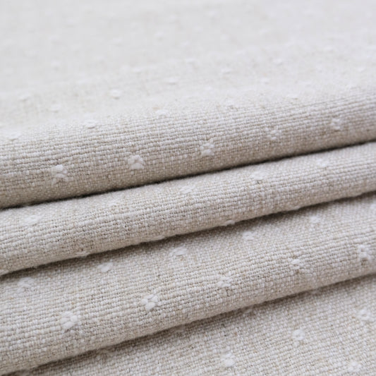 A close-up view of a folded fabric with a textured, beige-colored appearance.