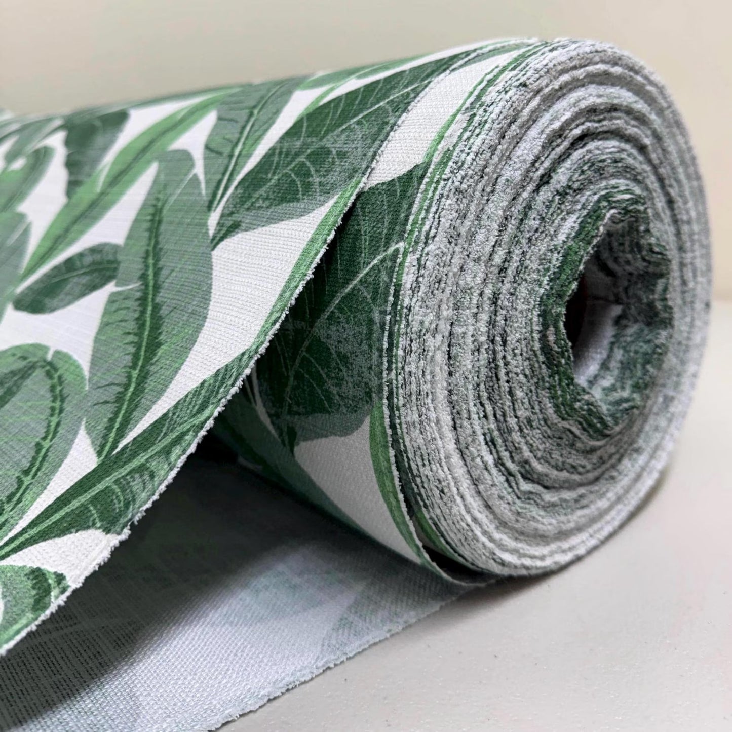 A roll of fabric with a green leaf pattern is shown in the image.