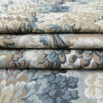 a close-up view of a fabric with a floral pattern in shades of blue, green, and beige. The fabric appears to be folded or rolled, revealing the intricate design and texture of the material.