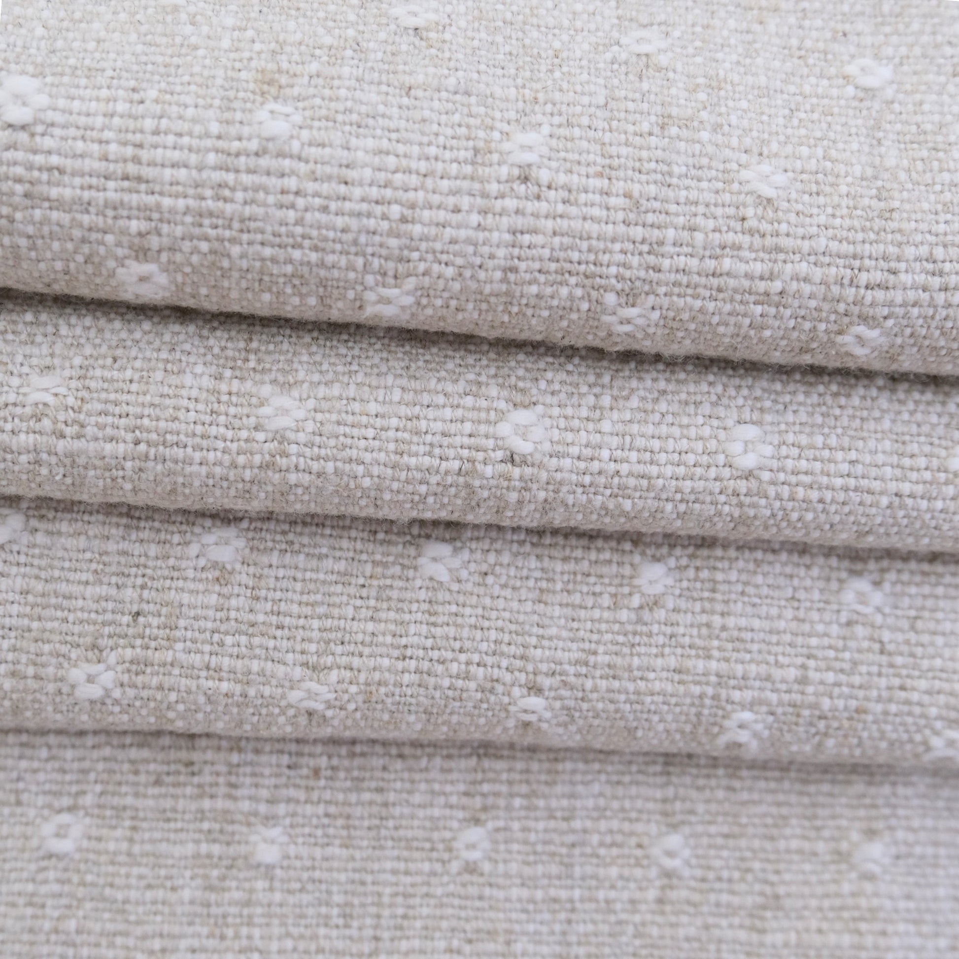 A close-up view of a fabric with a textured, woven pattern in shades of beige and white.