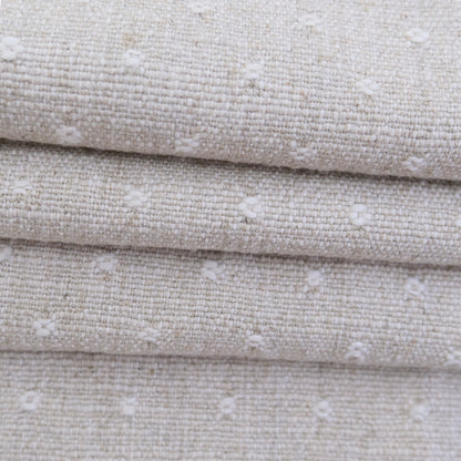 A close-up view of a fabric with a textured, woven pattern in shades of beige and white.