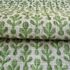 a close-up view of a fabric with a repeating pattern of green cactus leaves. The pattern is woven into the fabric, creating a textured and visually appealing design.