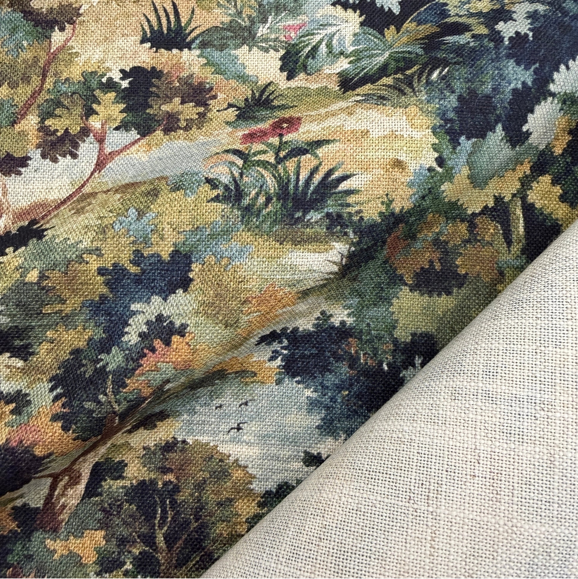 The image is a close-up of a fabric with a vibrant, colorful print depicting a lush, tropical landscape with various plants and trees.