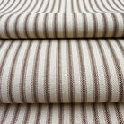 a close-up view of a fabric with a striped pattern in shades of brown and white. The fabric appears to be folded or stacked, creating a layered effect.