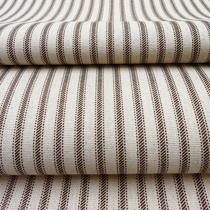 a close-up view of a fabric with a striped pattern in shades of brown and white. The fabric appears to be folded or stacked, creating a layered effect.