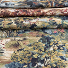 a close-up view of a fabric with a detailed landscape pattern, including trees, bushes, and flowers in various shades of green, brown, and red.