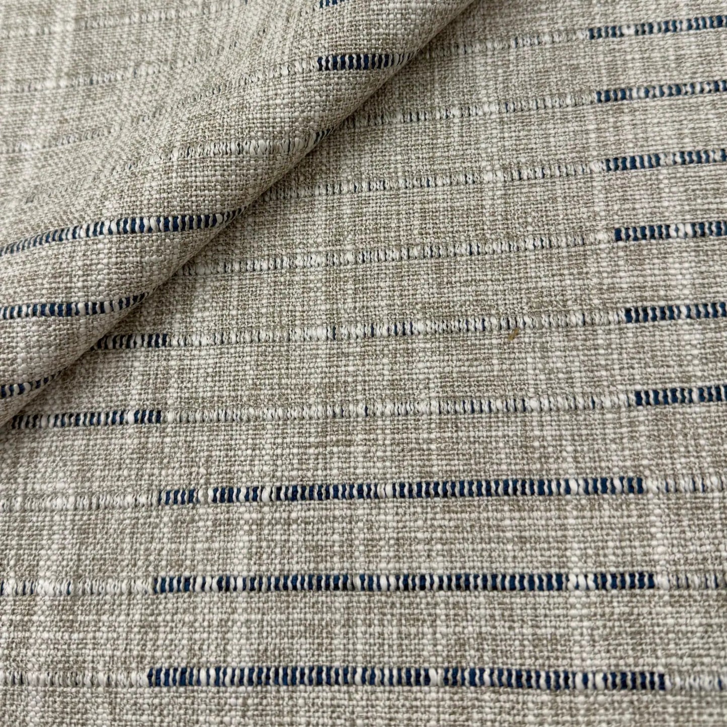 a close-up view of a textured fabric with a striped pattern in shades of gray and blue.