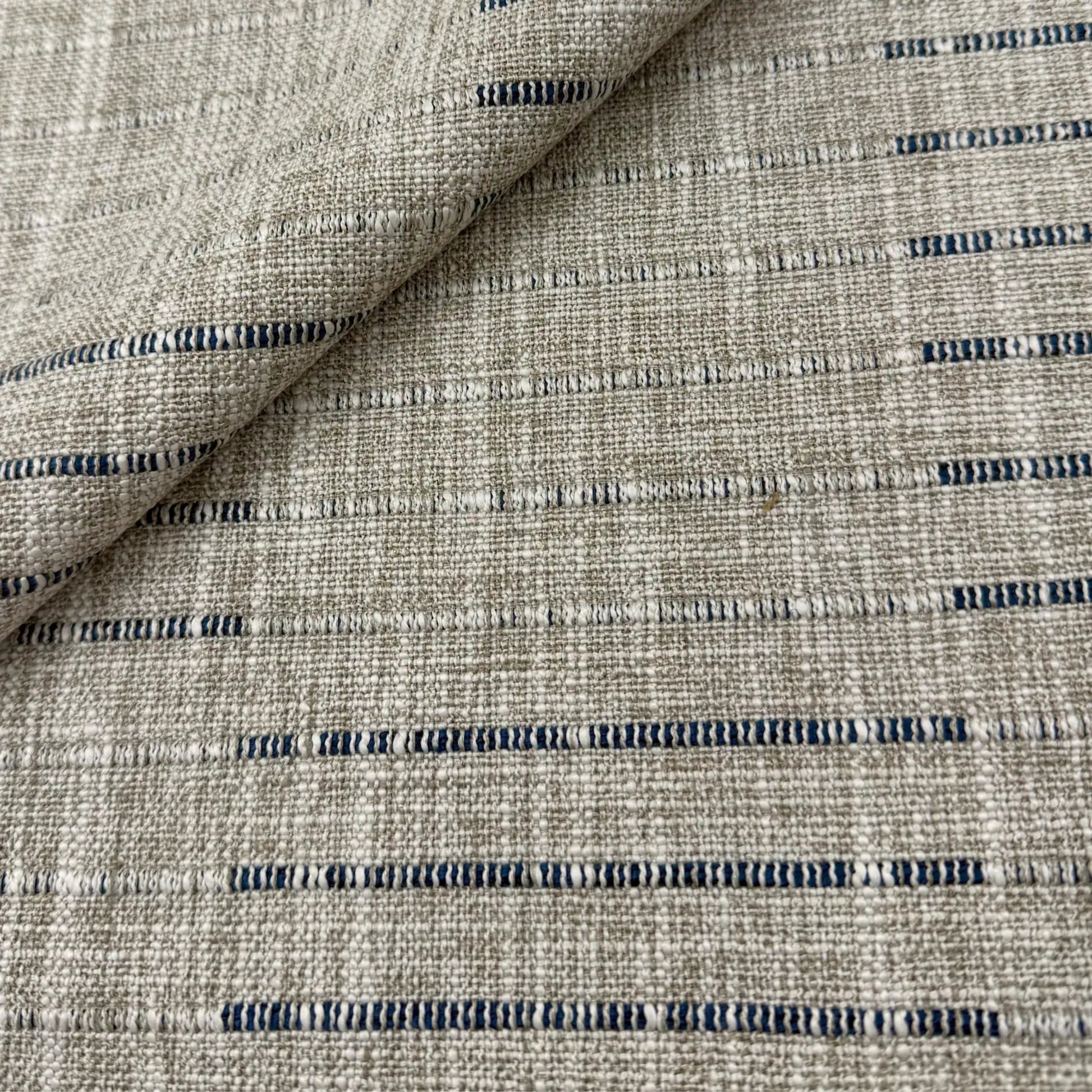 a close-up view of a textured fabric with a striped pattern in shades of gray and blue.
