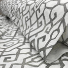 a close-up view of a fabric with a repeating pattern of geometric shapes in shades of gray and white.