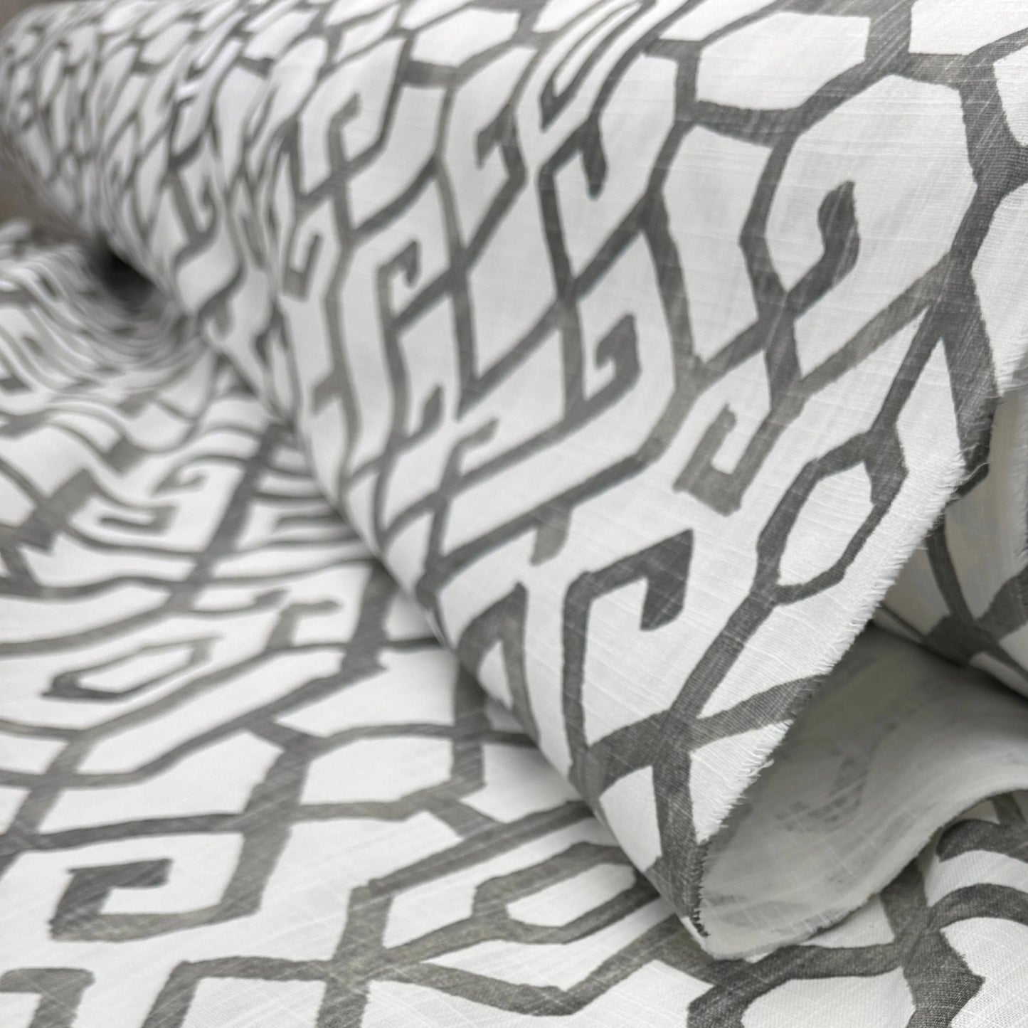 a close-up view of a fabric with a repeating pattern of geometric shapes in shades of gray and white.