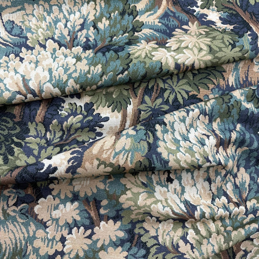 a close-up view of a fabric with a detailed, intricate floral pattern in shades of blue, green, and white. The fabric appears to be folded or rolled, revealing the intricate design and texture of the pattern.