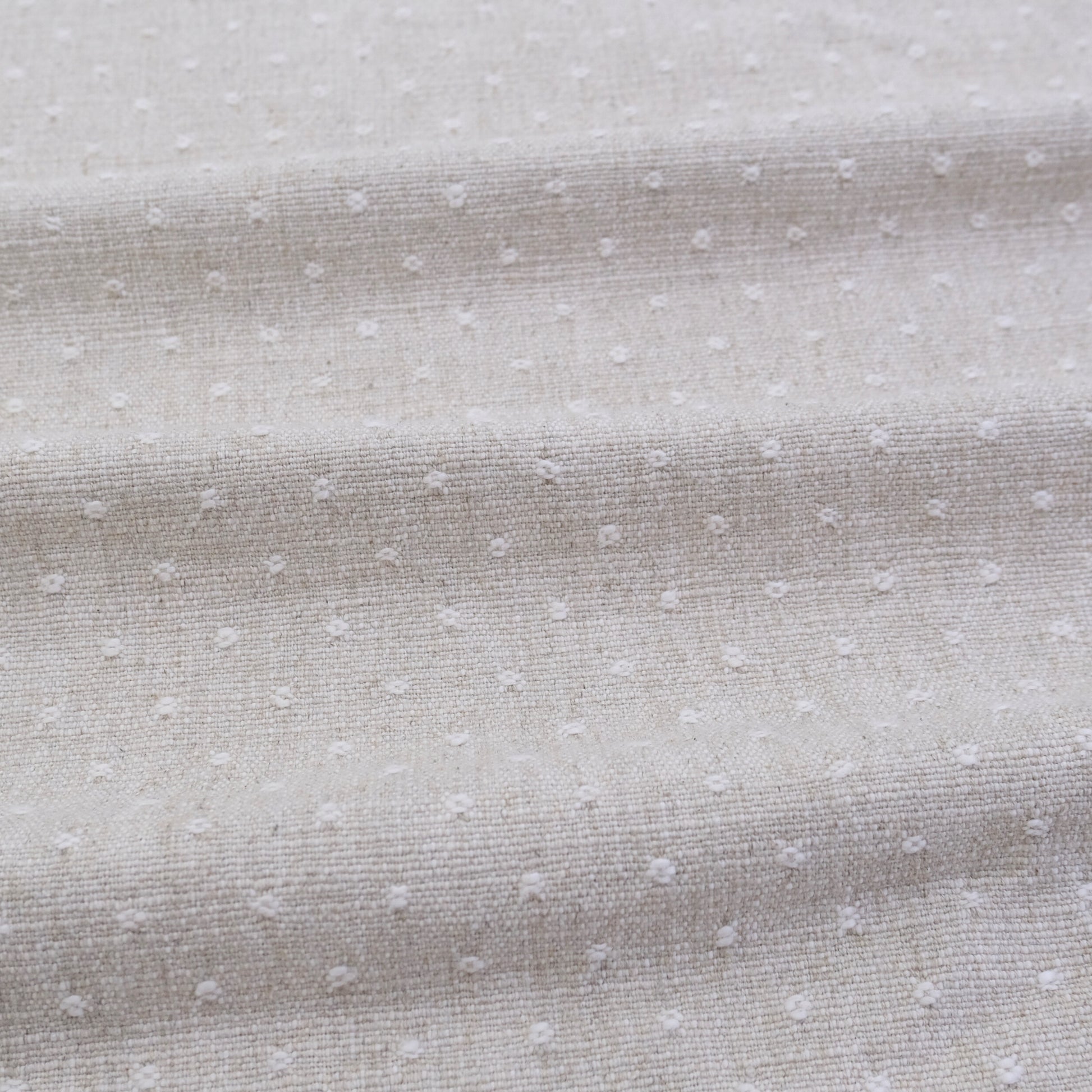 a close-up view of a fabric with small white dots or polka dots, creating a textured and patterned appearance.