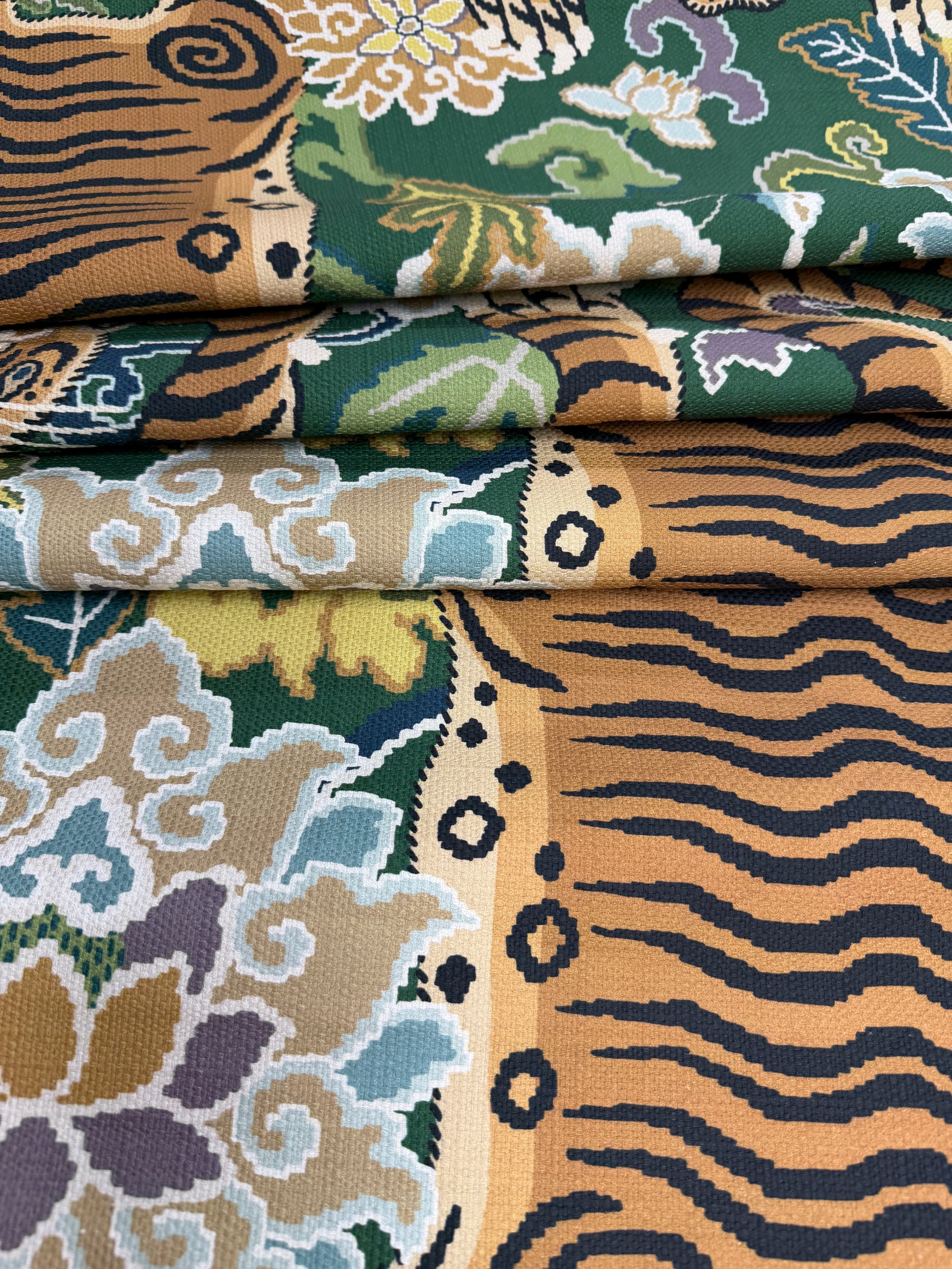 Folded layers of emerald green tiger print fabric highlighting the high-quality weight of the upholstery-grade cotton.