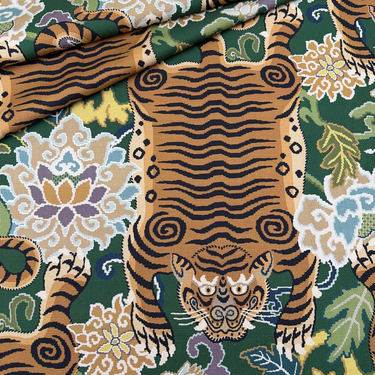 A close-up view of the emerald green tiger fabric draped to show how the pattern looks on curved furniture or pillows.