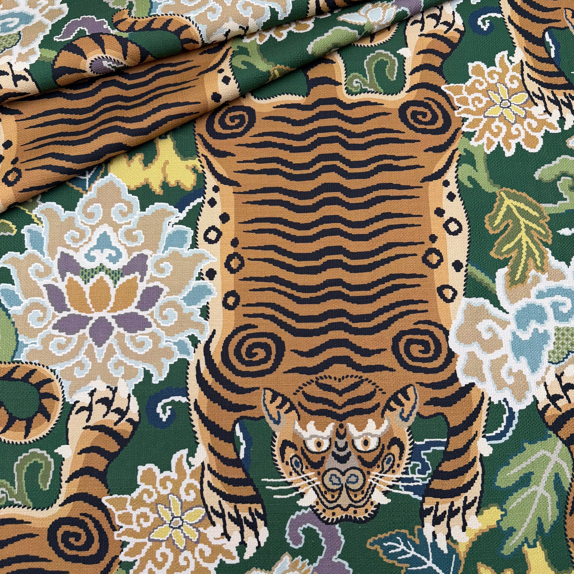 A close-up view of the emerald green tiger fabric draped to show how the pattern looks on curved furniture or pillows.