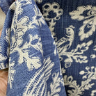 Blue and cream floral upholstery fabric held to show thickness, texture, and drape