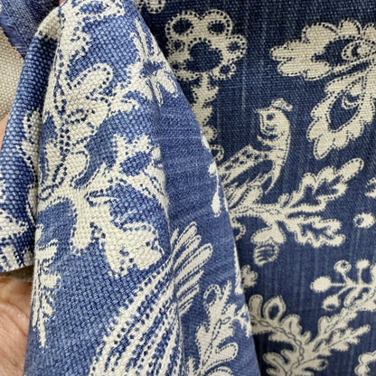 Blue and cream floral upholstery fabric held to show thickness, texture, and drape