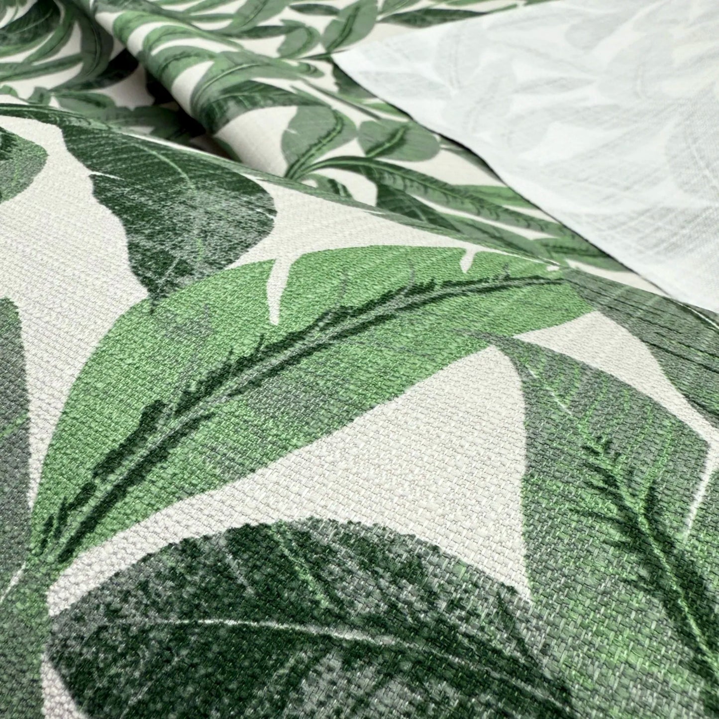 a close-up view of a fabric with a repeating pattern of green leaves. The leaves are arranged in a way that creates a textured and visually appealing design.