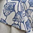 Blue ginkgo leaf print fabric folded to display pattern scale and natural linen texture