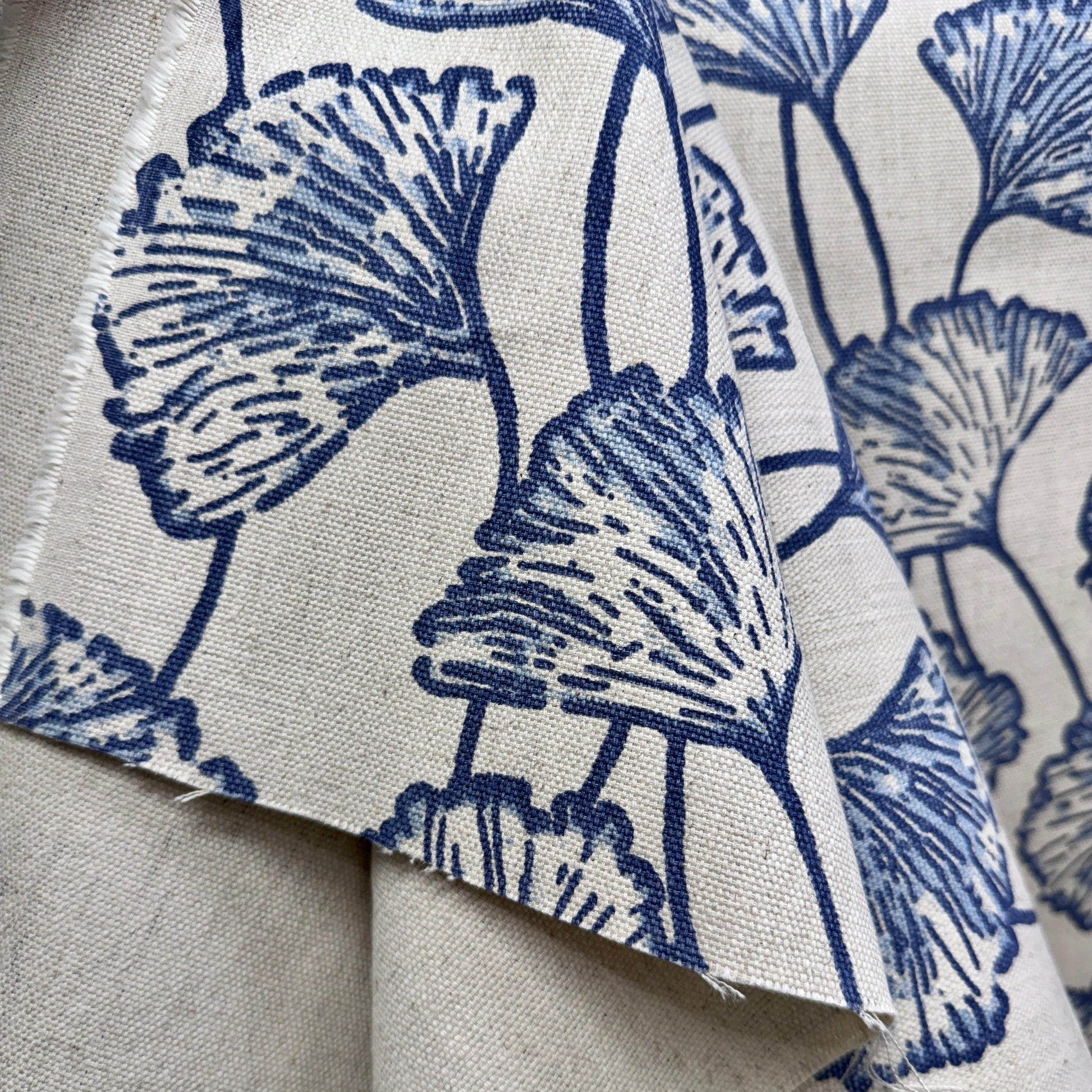 Blue ginkgo leaf print fabric folded to display pattern scale and natural linen texture