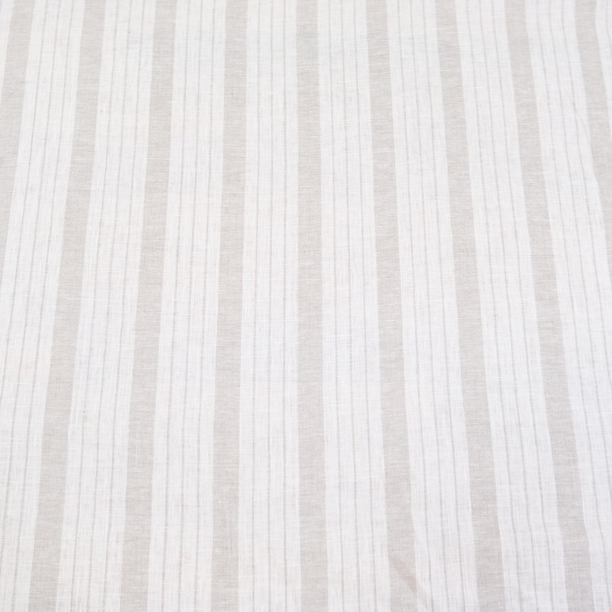 Flat lay of taupe striped linen fabric showing even balanced stripes and neutral color tones. The fabric’s light drape makes it perfect for farmhouse style drapery, rustic table runners, DIY napkins, and cottage-style crafts. This striped linen is a versatile choice for sewing enthusiasts looking to create timeless, minimalist home décor items with natural linen texture and neutral earthy stripes.