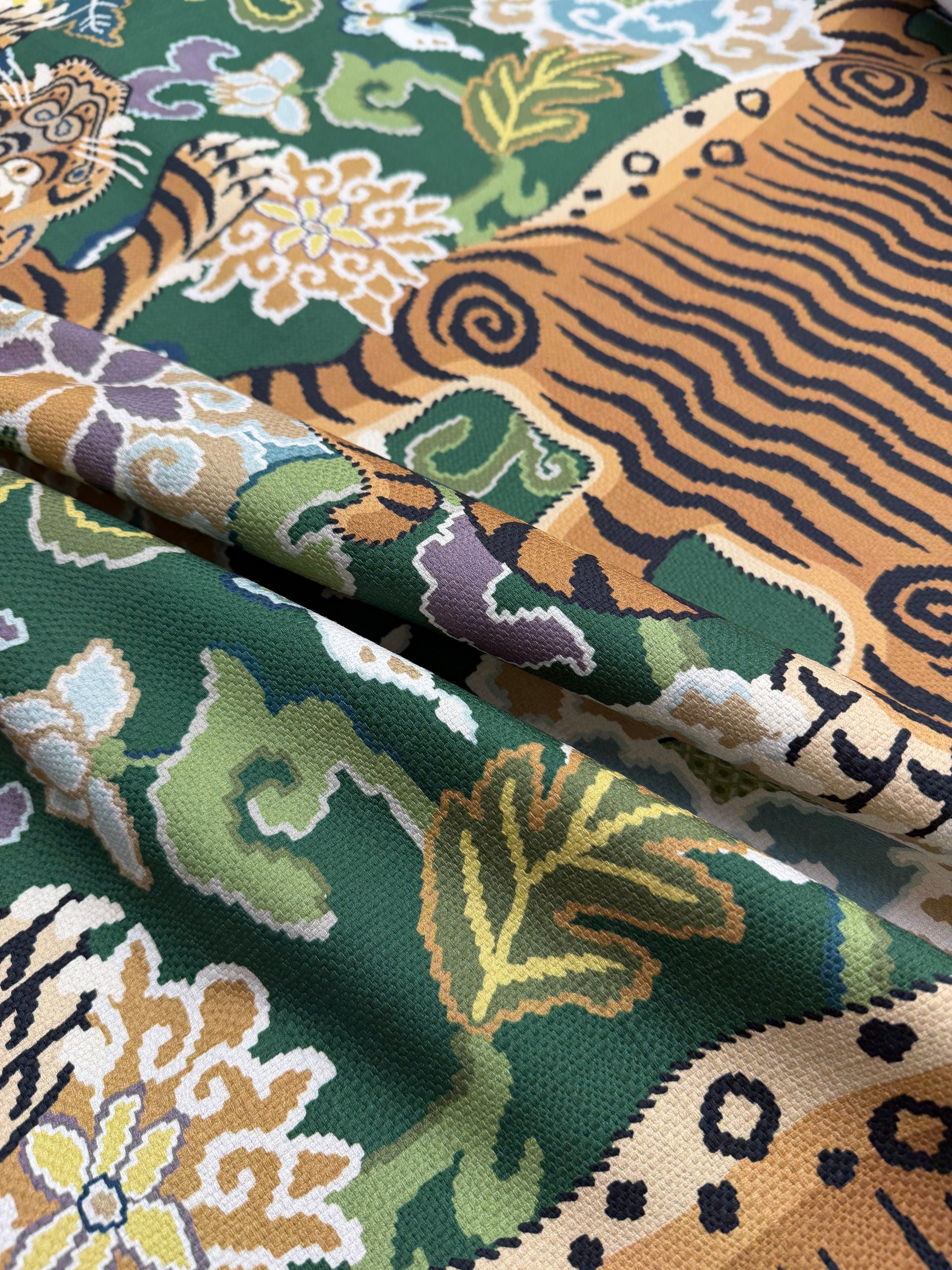 Close-up of draped 100% cotton emerald green tiger fabric showing the textile's soft texture and rich jewel-tone color.