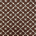 a close-up view of a fabric with a repeating pattern of brown and white flowers or designs. The pattern is intricate and detailed, with the flowers or designs appearing in various sizes and orientations. The fabric appears to be made of a woven material, and there is a ruler placed at the bottom of the image for scale.