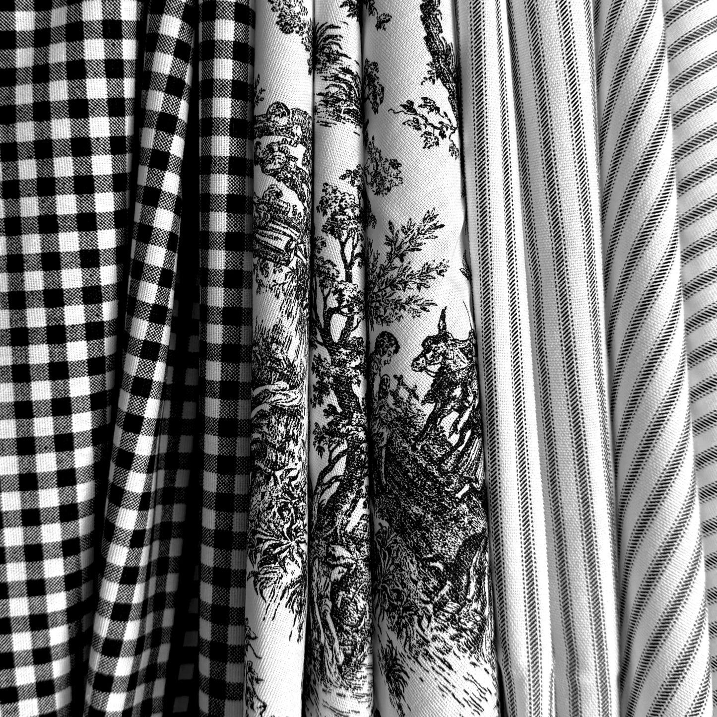 A close-up view of several fabric swatches, including a black and white checkered fabric, a fabric with a black and white floral pattern, and a fabric with a striped pattern.
