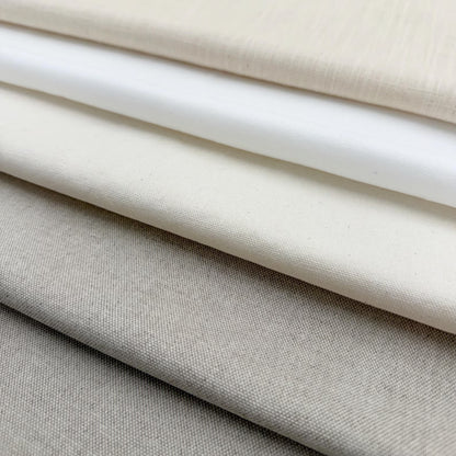 A close-up image of various fabric swatches in shades of white, gray, and beige, arranged in a layered fashion.