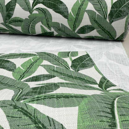 a close-up view of a fabric with a repeating pattern of green leaves, likely palm leaves, against a white background.