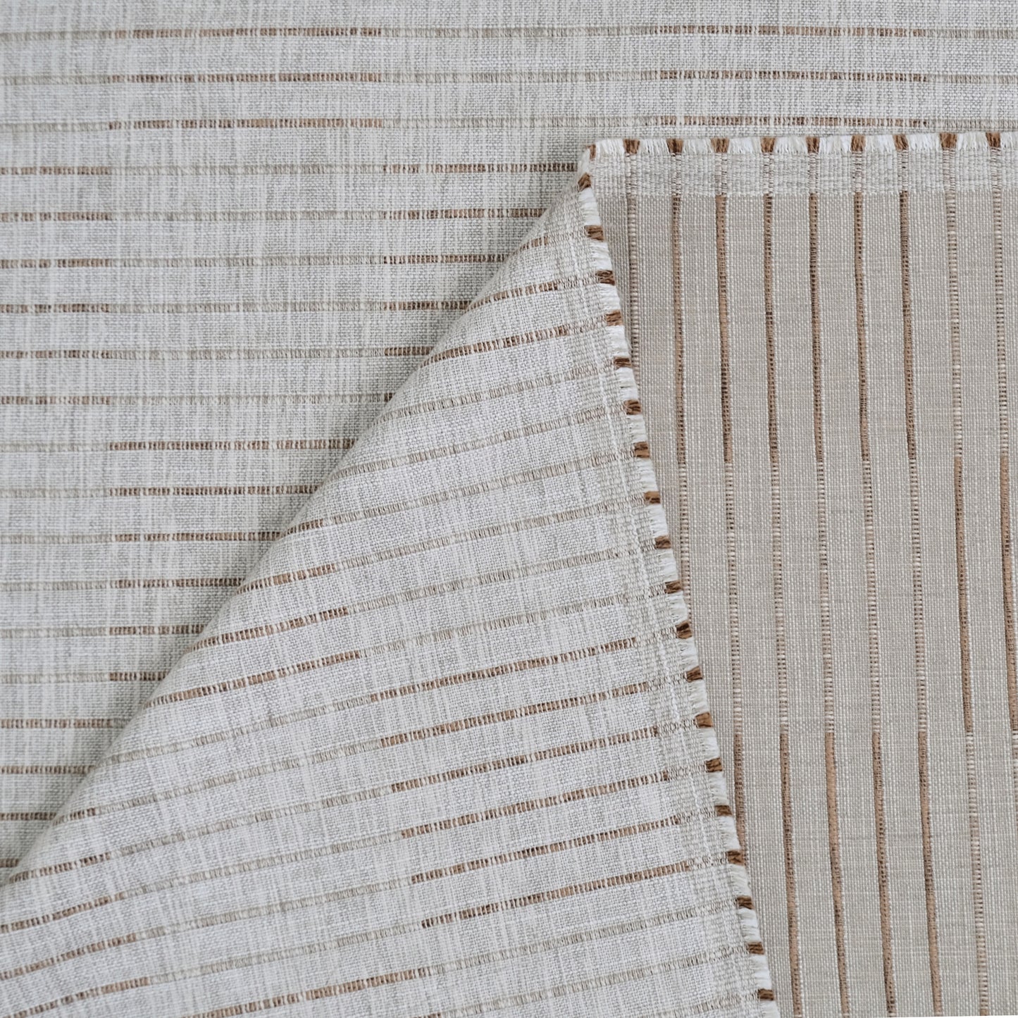 a close-up view of a fabric with a striped pattern, featuring a diagonal line running across it. The fabric appears to be made of a light-colored material, possibly linen or cotton, with a textured appearance.