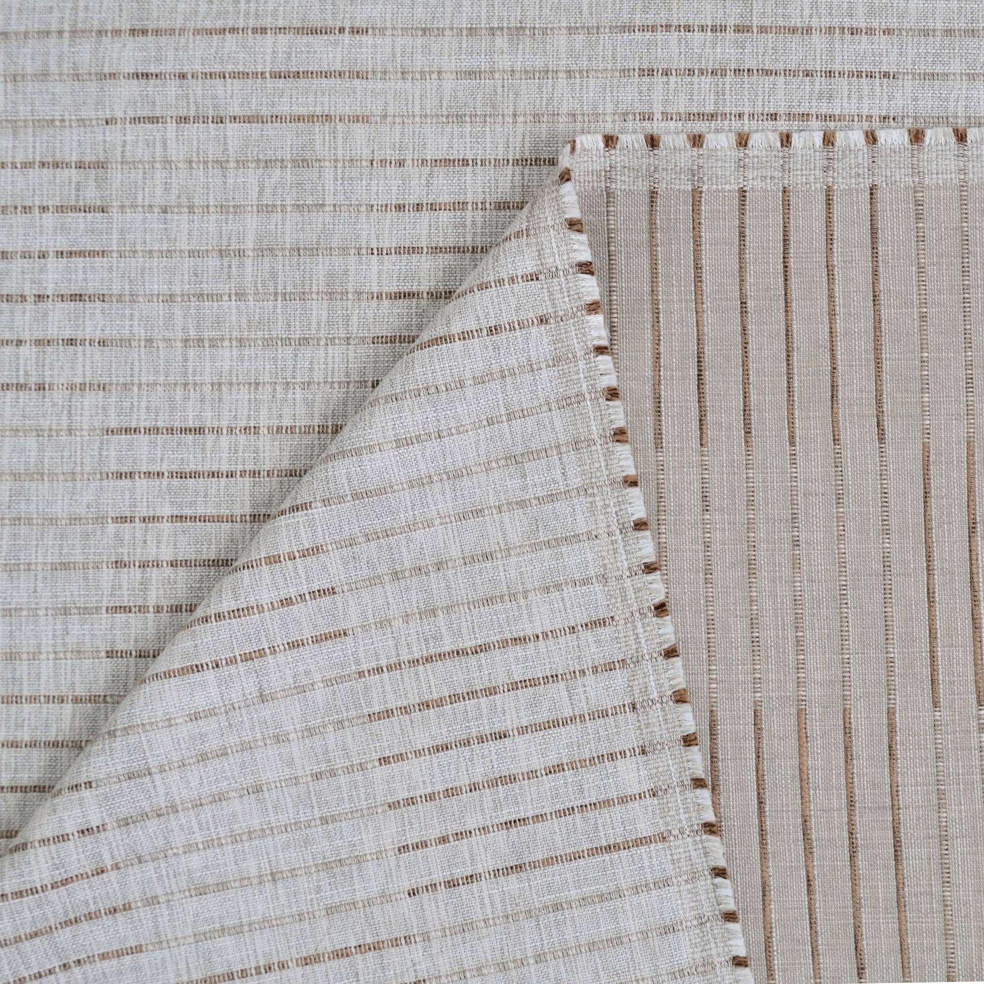 a close-up view of a fabric with a striped pattern, featuring a diagonal line running across it. The fabric appears to be made of a light-colored material, possibly linen or cotton, with a textured appearance.