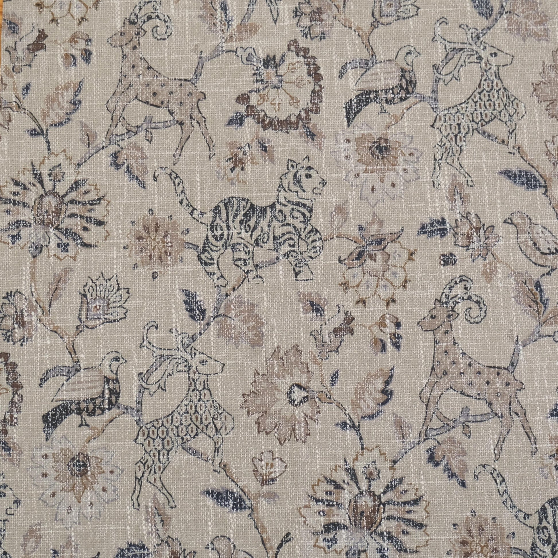 Beige fabric with a repeating pattern of stylized animals and floral elements. The design features a deer, tiger, and birds among ornate flowers and foliage. The color palette includes shades of brown, beige, and hints of green, creating a vintage, textured look.