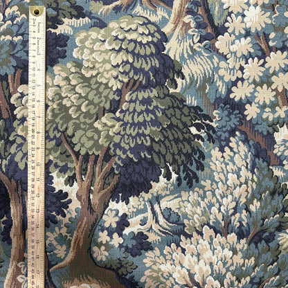 a detailed tapestry or fabric with a lush, forest-like scene, including trees, bushes, and flowers in various shades of green, blue, and brown. The fabric appears to be a textile or fabric with a natural, botanical motif.