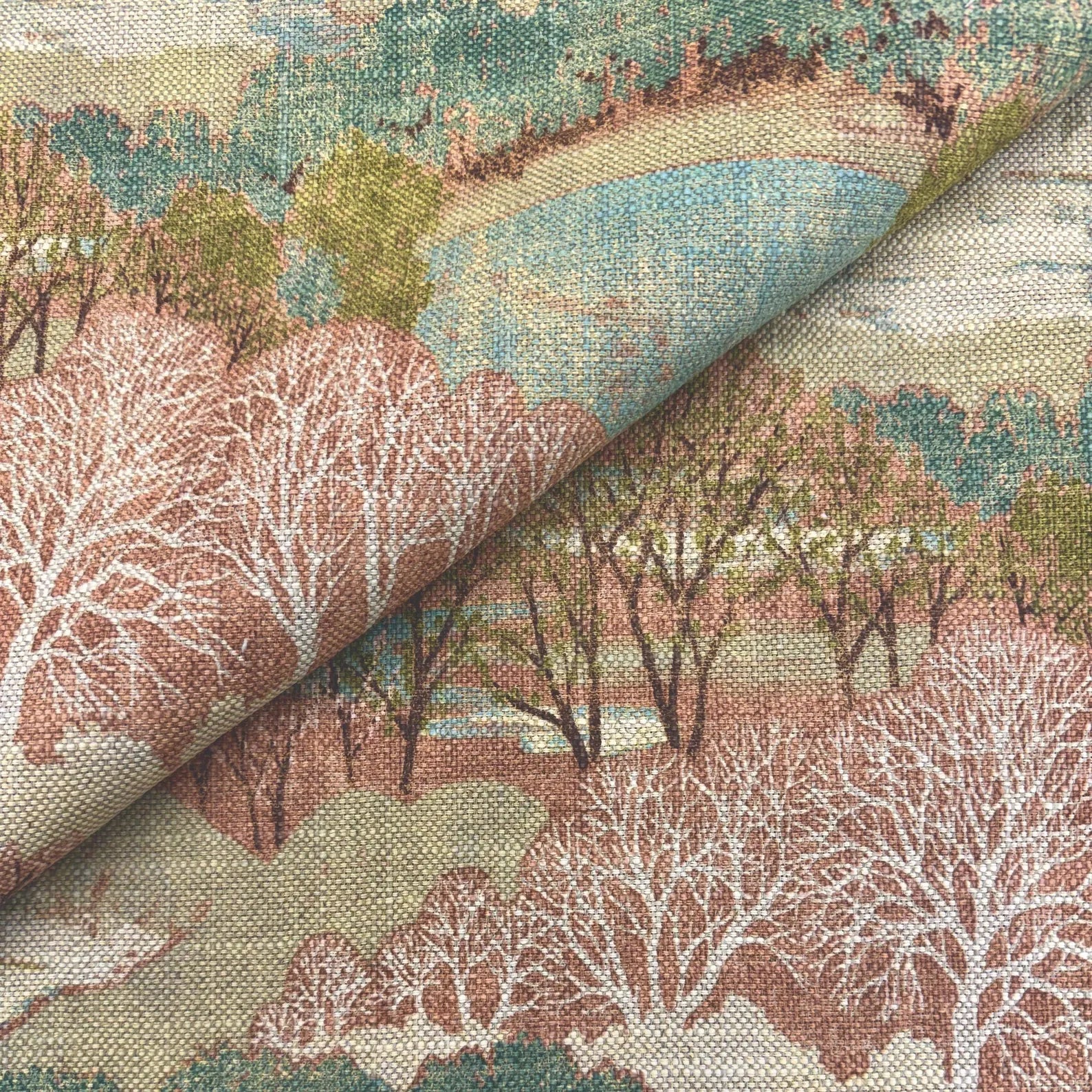 Diagonal fold of Pink Scenic Forest Fabric highlighting the drape and weight of the cotton material.