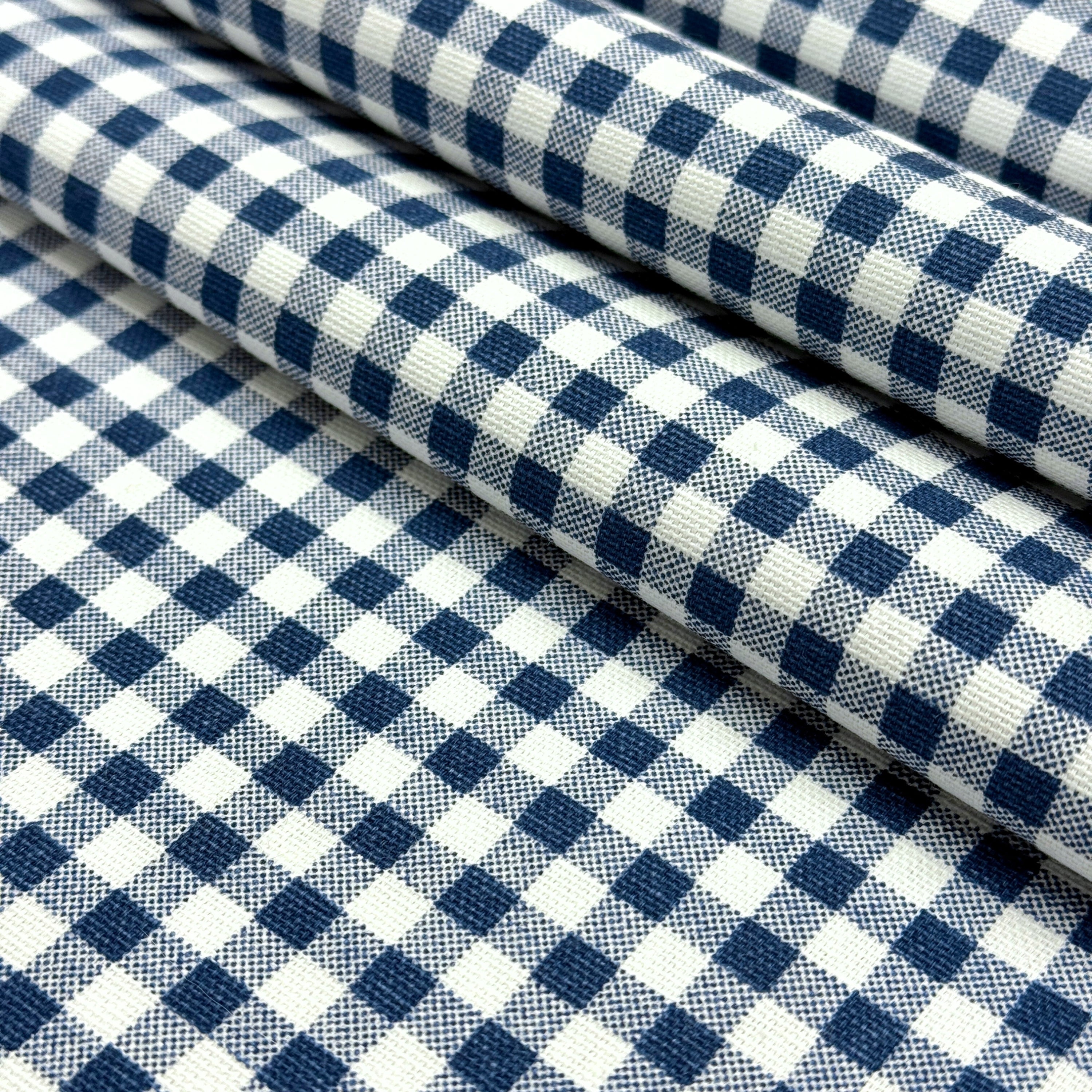 a close-up view of a fabric with a blue and white checkered pattern. The fabric appears to be folded or rolled up, creating a visually appealing and textured design.