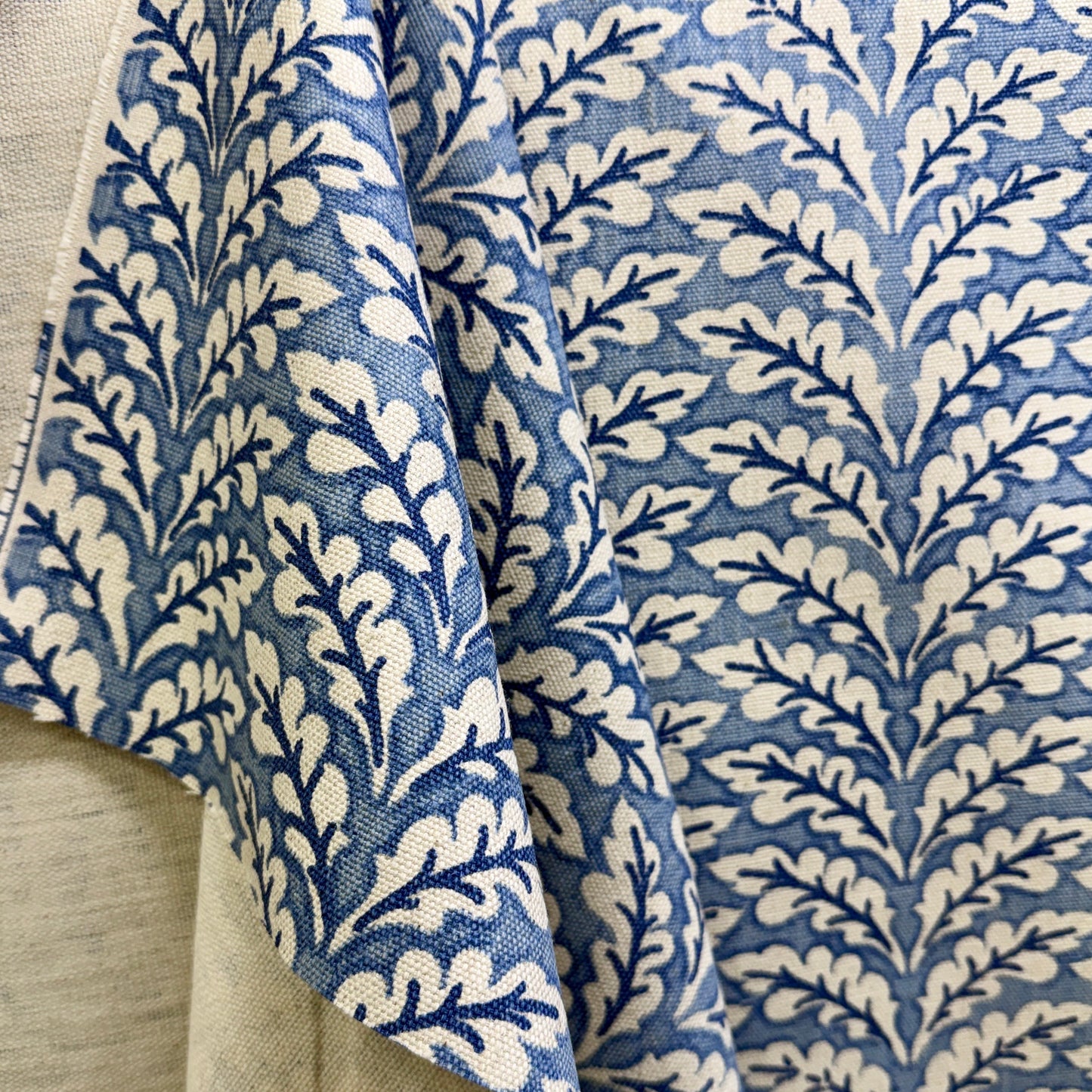 Blue floral vine fabric in soft folds showing repeating botanical pattern design