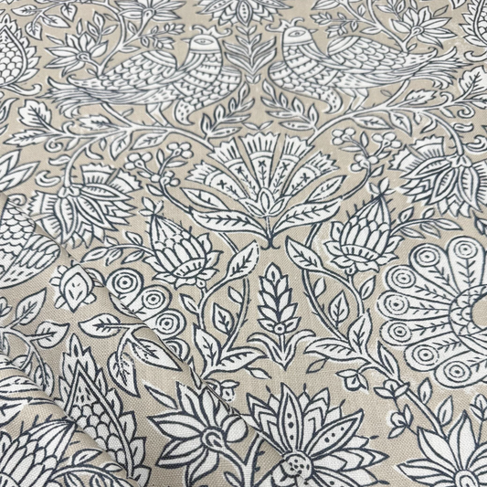 a close-up view of a fabric with a repeating floral pattern in shades of beige and black. The pattern consists of various flowers and leaves, creating a visually striking and intricate design. The image does not contain any text or other discernible objects or actions.