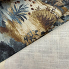 a close-up view of a fabric with a floral pattern, featuring various shades of blue, brown, and green. The fabric appears to be a piece of linen or a similar material, with a textured and woven appearance.