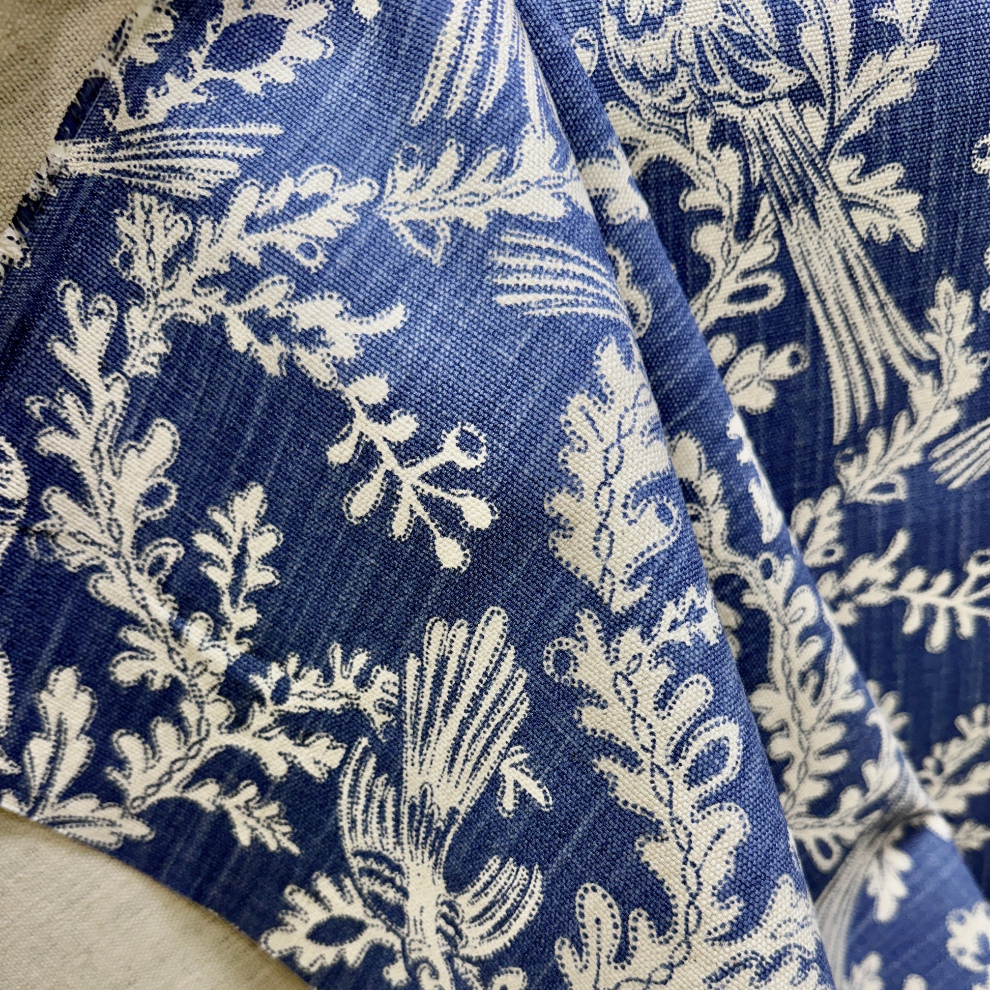 Close-up of blue floral fabric with cream botanical pattern and detailed vine design