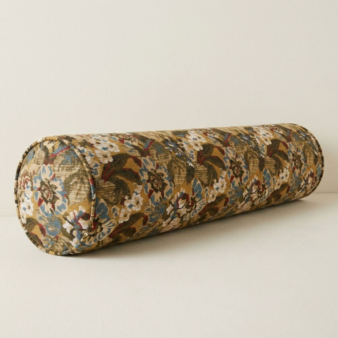 A long, cylindrical pillow with a floral pattern in shades of brown and green.