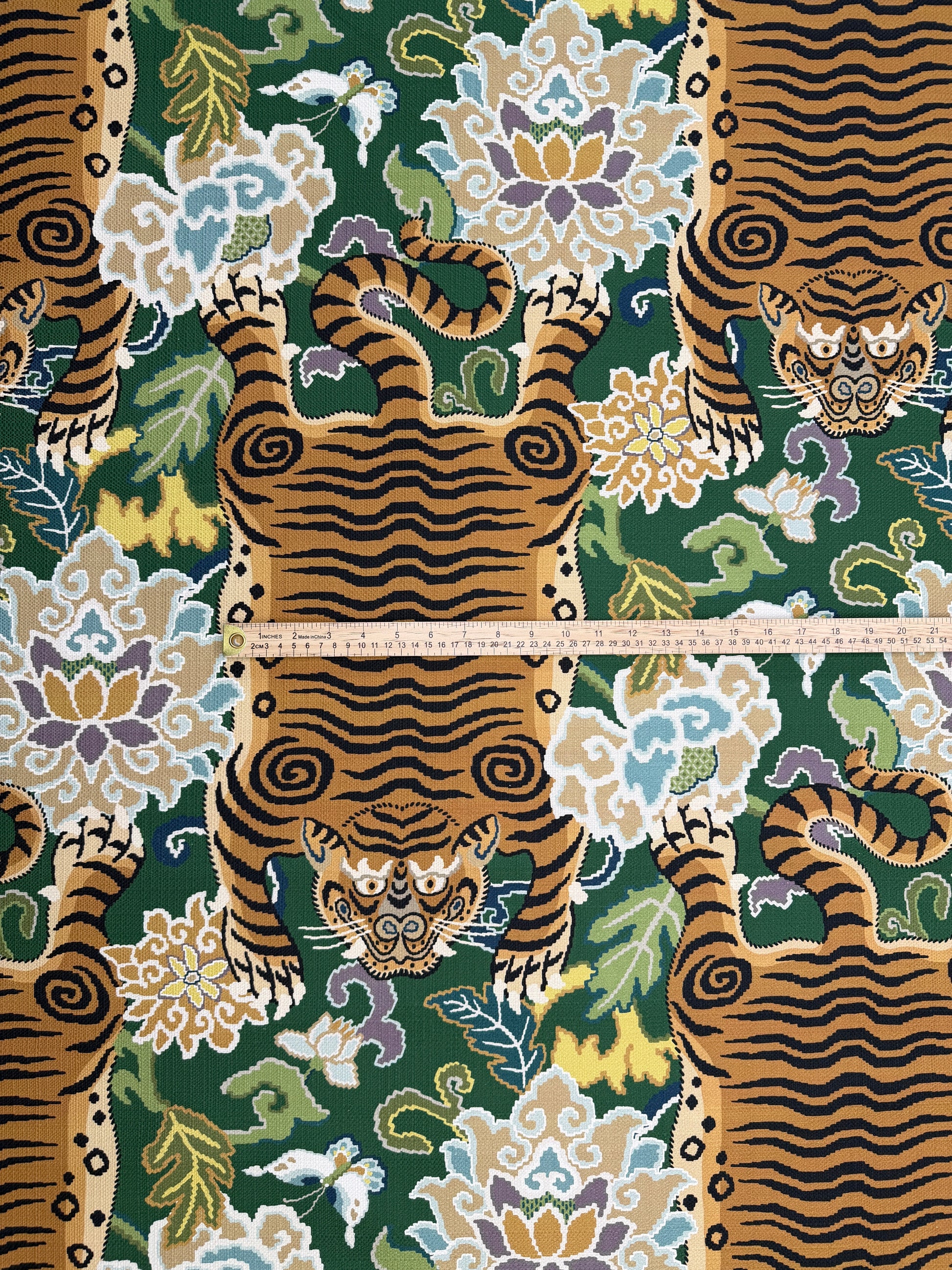 Scale reference with a ruler measuring the width of the tiger motif on emerald green chinoiserie fabric.