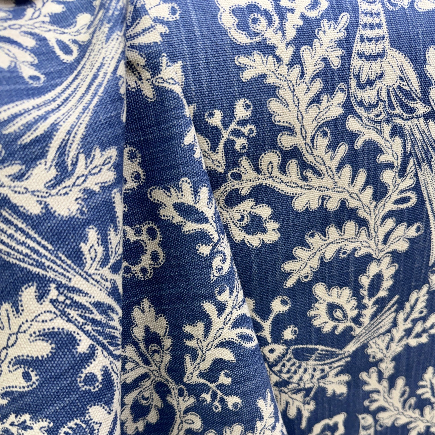 Blue and cream botanical fabric with floral vine pattern draped to show texture and detail