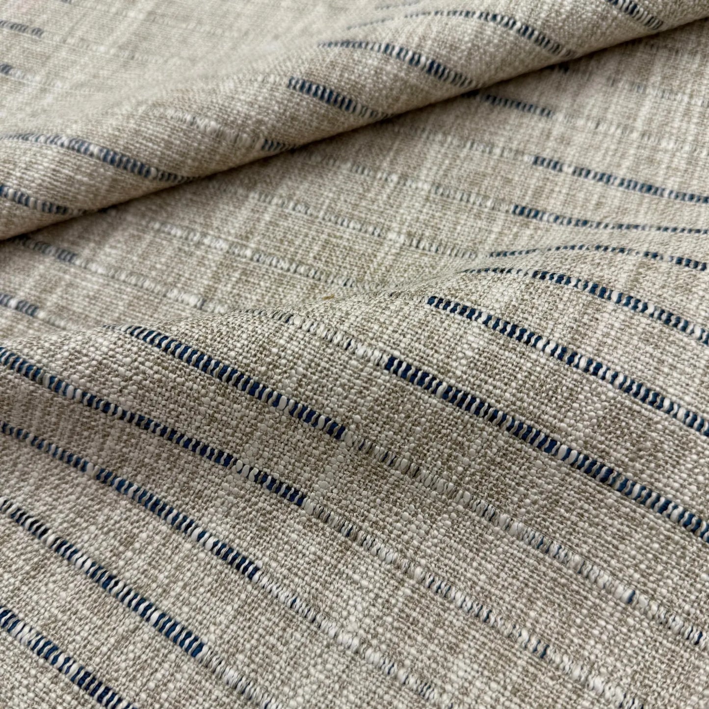 a close-up view of a fabric with a striped pattern in shades of beige and blue.