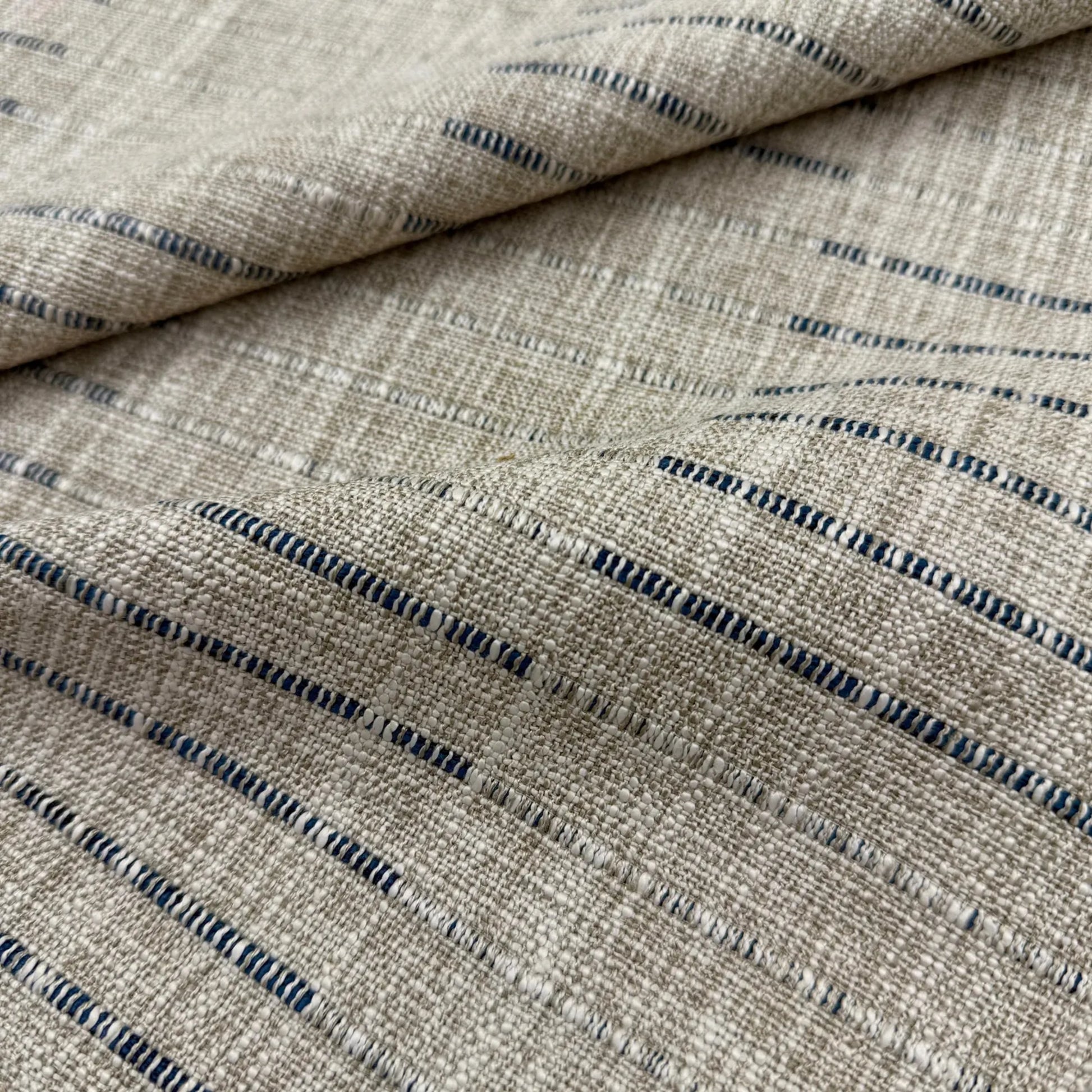 a close-up view of a fabric with a striped pattern in shades of beige and blue.