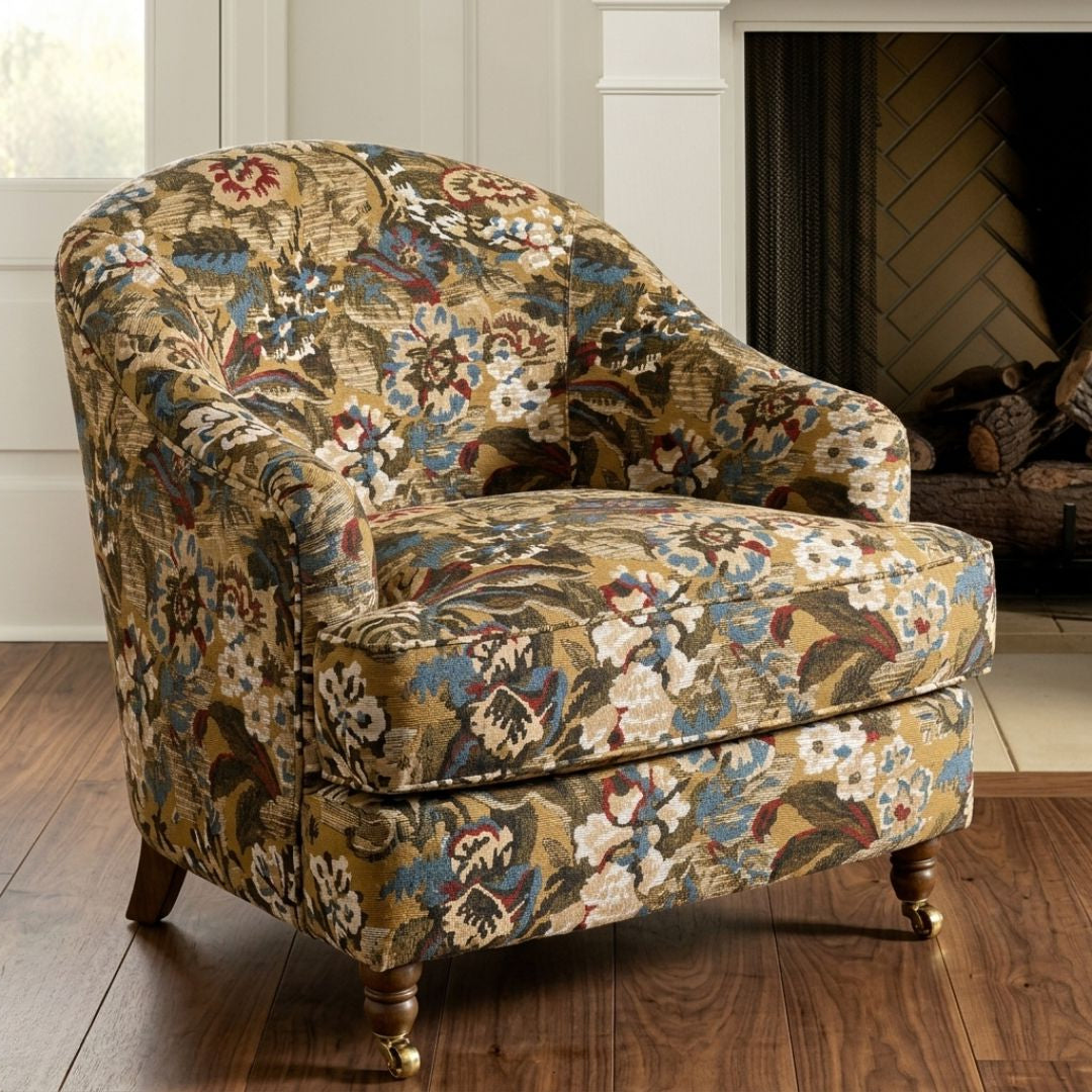 A floral patterned armchair with a wooden frame and legs, placed in front of a fireplace.