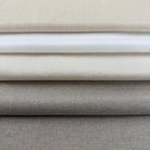 A close-up image of a stack of fabric swatches in various shades of gray and beige.