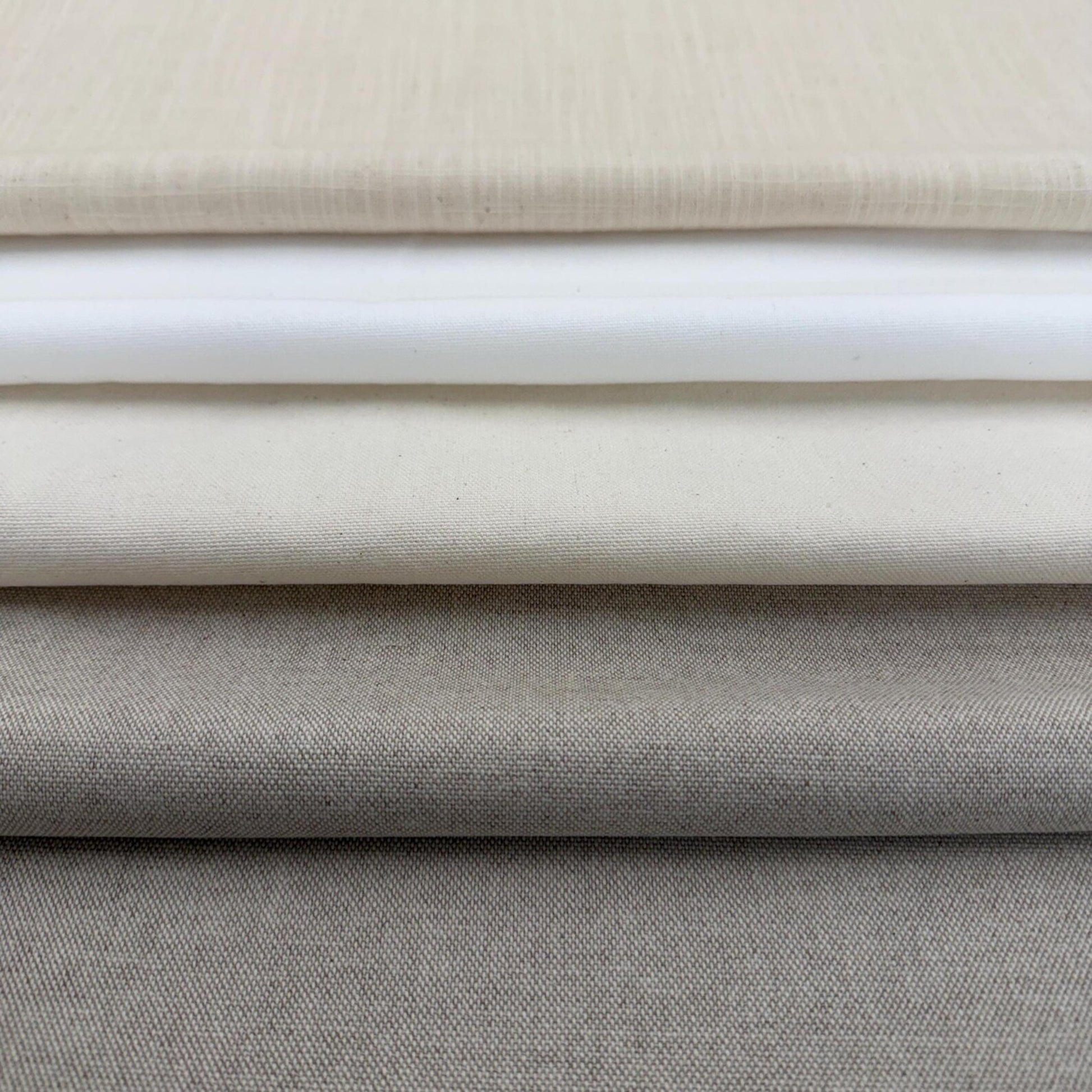 A close-up image of a stack of fabric swatches in various shades of gray and beige.