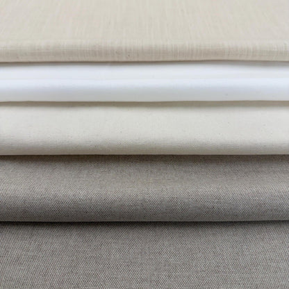 A close-up image of a stack of fabric swatches in various shades of gray and beige.